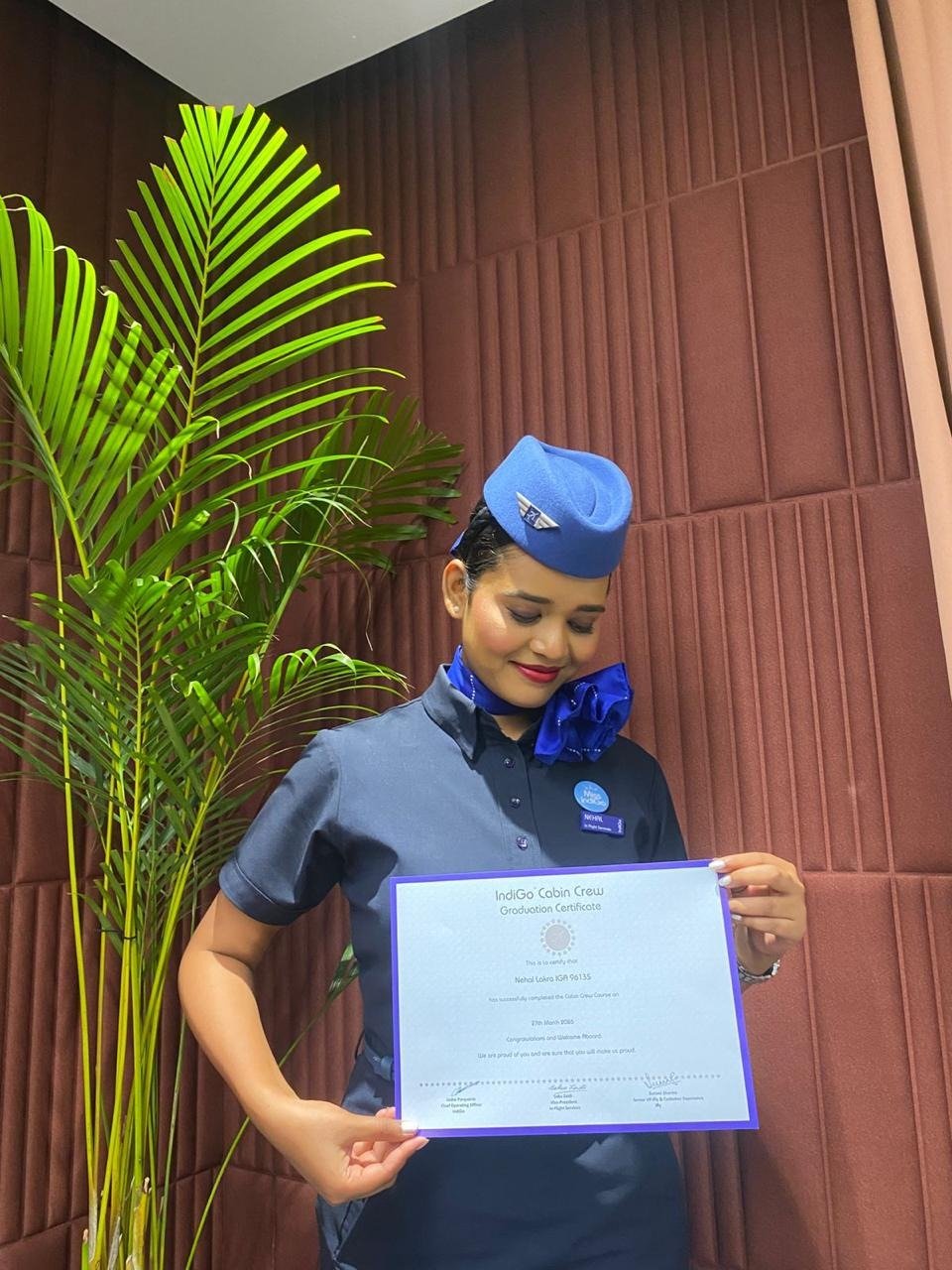 Cabin crew graduate in uniform holding her training graduation certificate